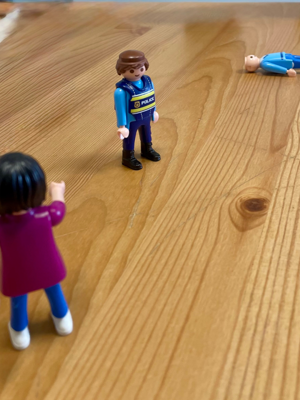 Figuras de juguete colocadas sobre una mesa de madera para representar una situación vivida, técnica utilizada en terapia de trauma